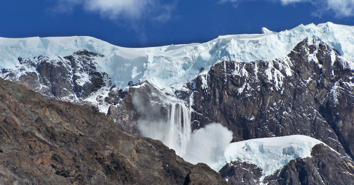 A large waterfall over a snow covered mountain