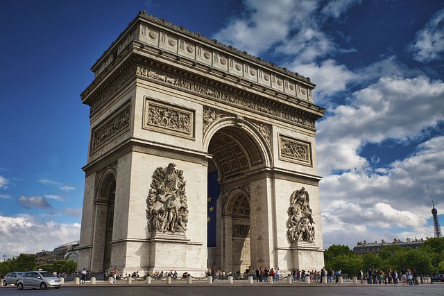 A large clock tower in front of Arc de Triomphe